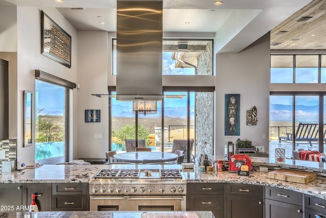 kitchen featuring a healthy amount of sunlight, light stone countertops, double oven range, and a high ceiling