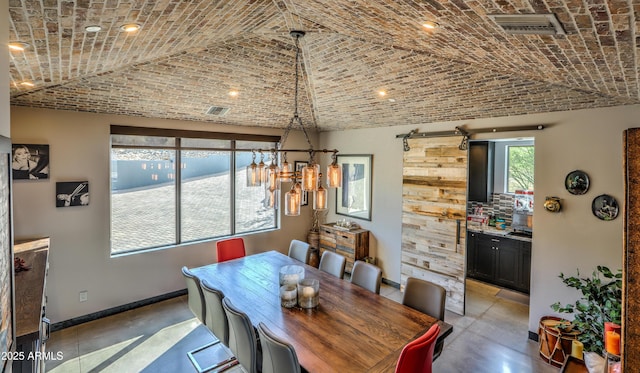 dining room featuring brick ceiling, visible vents, baseboards, and a barn door