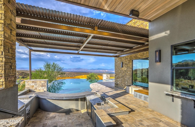 view of patio featuring exterior kitchen and a pergola