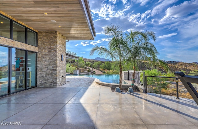 view of patio featuring an infinity pool and a mountain view