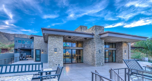 back of property featuring stone siding and a patio area