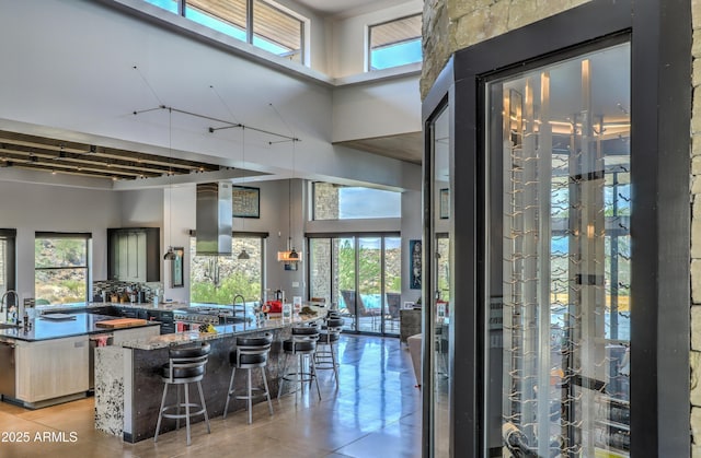 interior space with light tile patterned floors, a high ceiling, a breakfast bar, and a large island with sink