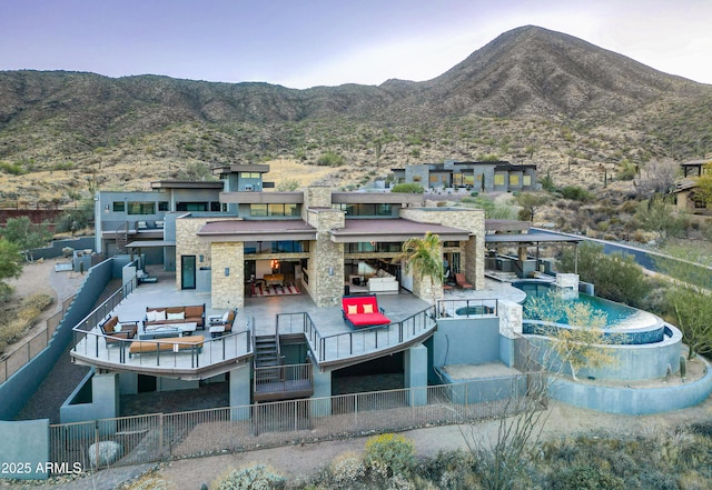 rear view of house with a pool with connected hot tub, a patio area, a mountain view, and fence