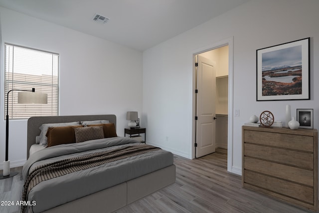 bedroom with a spacious closet and light wood-type flooring