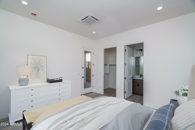 bedroom with ensuite bath, a spacious closet, a closet, and wood-type flooring