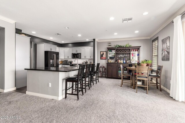 2425 W Bronco Butte Trl Unit 2028, Phoenix, AZ 85085 - kitchen with high end black refrigerator, light colored carpet, ornamental molding, a breakfast bar area, and baseboards