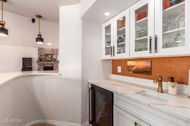 indoor bar featuring beverage cooler, a fireplace, and decorative light fixtures