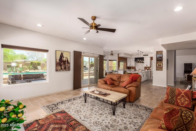 living area with stone tile flooring, a ceiling fan, recessed lighting, and baseboards