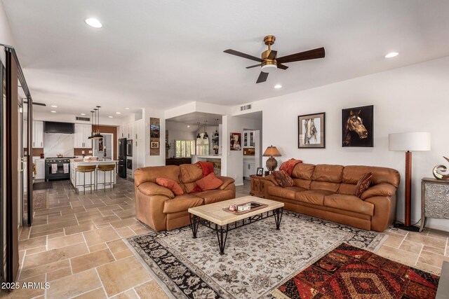 living room featuring ceiling fan, stone tile flooring, and recessed lighting