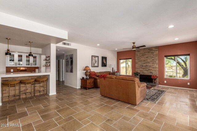 living area featuring healthy amount of natural light, a fireplace, ceiling fan, baseboards, and recessed lighting