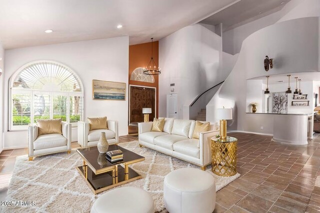 living area featuring high vaulted ceiling, stairway, baseboards, and stone finish floors