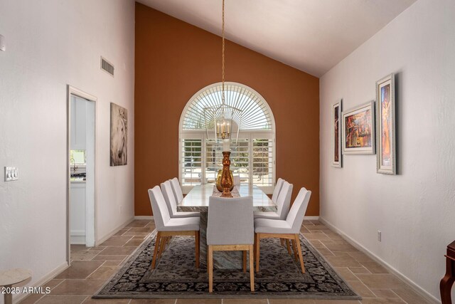 dining space featuring a chandelier, baseboards, high vaulted ceiling, and stone tile floors