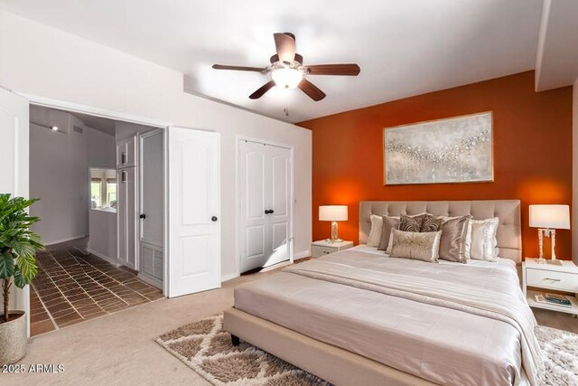 carpeted bedroom with a ceiling fan, multiple closets, and baseboards