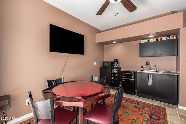 indoor wet bar with ceiling fan, stone tile floors, and baseboards