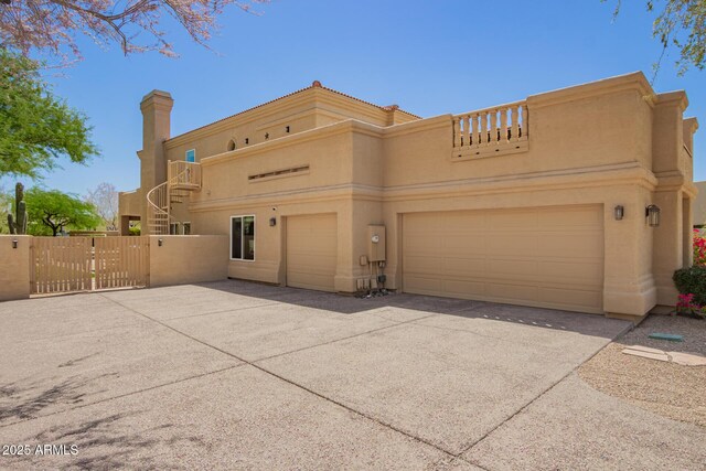 view of front of home with stucco siding, fence, a garage, a balcony, and a gate