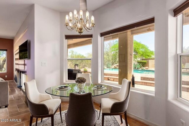 dining area featuring plenty of natural light, a chandelier, and stone finish floors