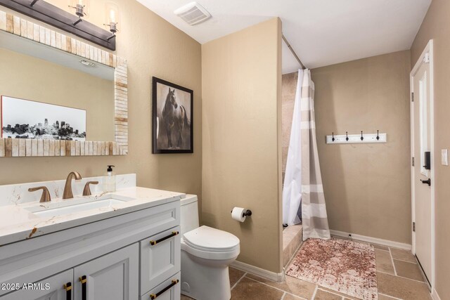 full bathroom featuring toilet, a shower with shower curtain, vanity, stone tile flooring, and baseboards