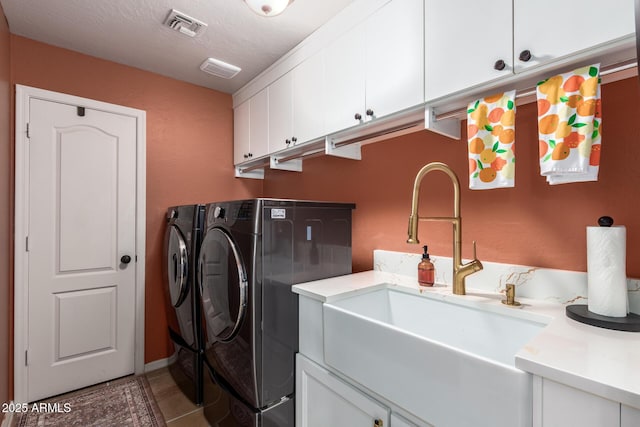 clothes washing area featuring washing machine and dryer, cabinet space, and light tile patterned floors
