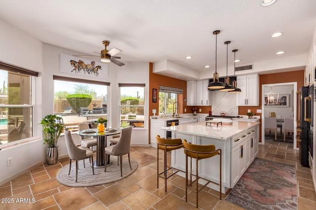 kitchen featuring white cabinets, recessed lighting, ceiling fan, a center island, and a kitchen bar