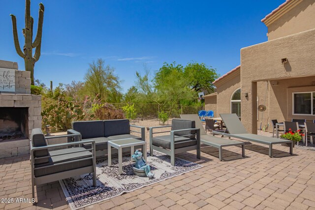 view of patio featuring outdoor dining area, an outdoor living space with a fireplace, and fence