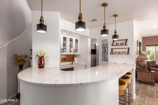 kitchen with white cabinets, glass insert cabinets, a peninsula, stone finish flooring, and recessed lighting
