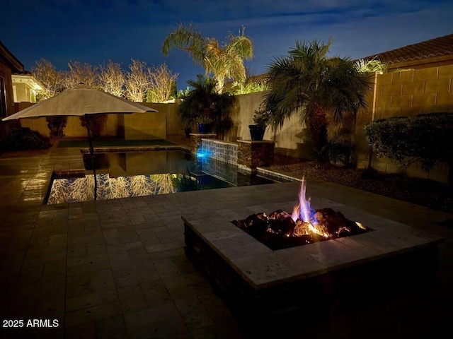 19571 E Strawberry Dr, Queen Creek, AZ 85142 - pool at night with a fenced backyard, a fenced in pool, a fire pit, and a patio area