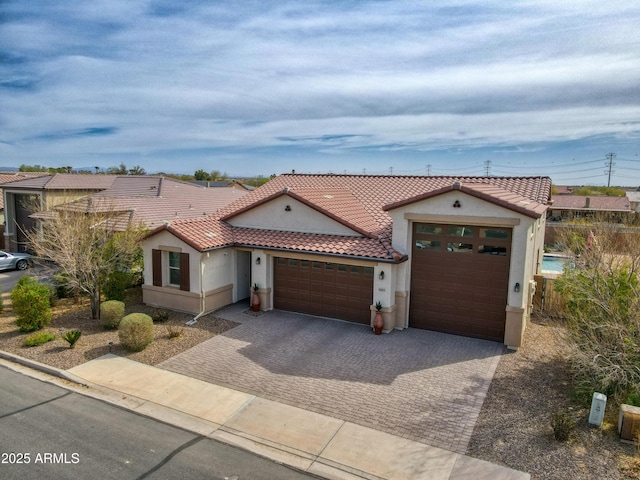 mediterranean / spanish home with a tiled roof, an attached garage, driveway, and stucco siding