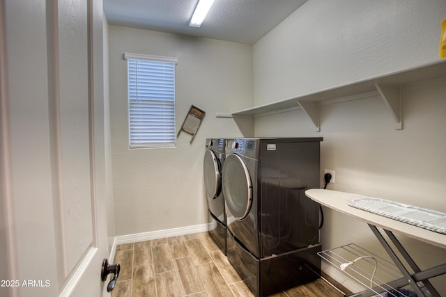 laundry room featuring wood finish floors, baseboards, washing machine and dryer, and laundry area