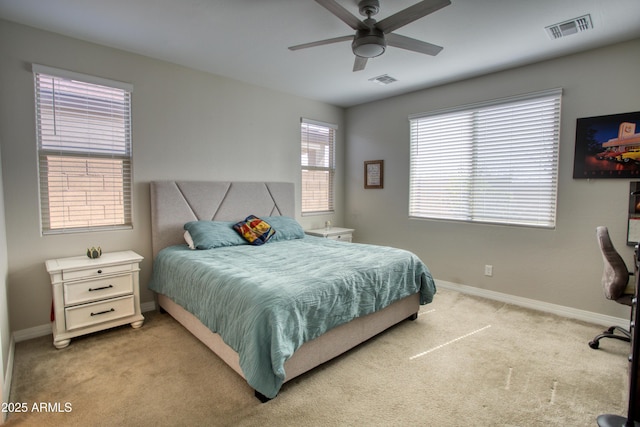 bedroom with visible vents, light colored carpet, baseboards, and ceiling fan