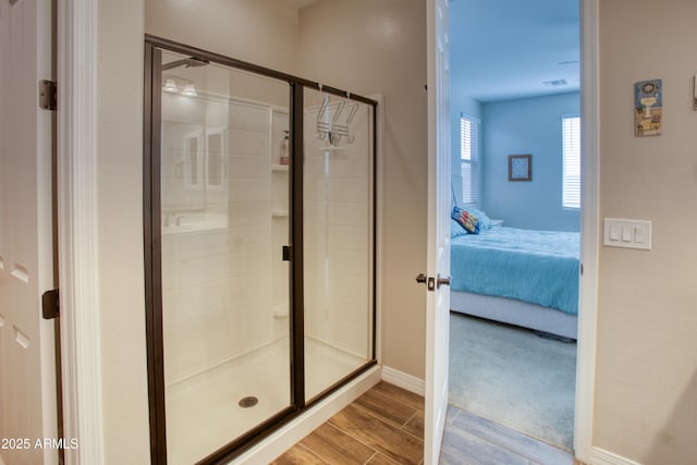 ensuite bathroom featuring wood finish floors, connected bathroom, visible vents, and a stall shower