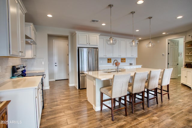 kitchen with visible vents, a sink, light countertops, appliances with stainless steel finishes, and exhaust hood