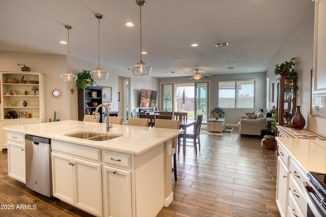 kitchen featuring a center island with sink, wood finish floors, a sink, stainless steel appliances, and open floor plan