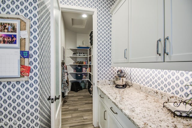 interior space featuring light stone counters, white cabinetry, light wood-style floors, and wallpapered walls