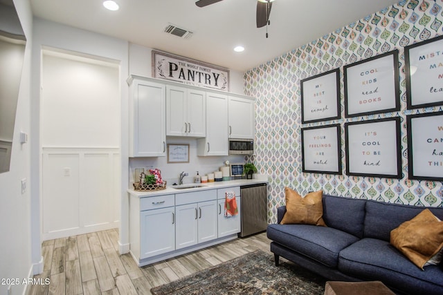 kitchen featuring visible vents, light wood-style flooring, a sink, wallpapered walls, and dishwasher