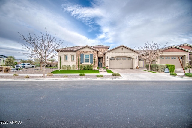 mediterranean / spanish-style house featuring stucco siding, driveway, stone siding, an attached garage, and a tiled roof