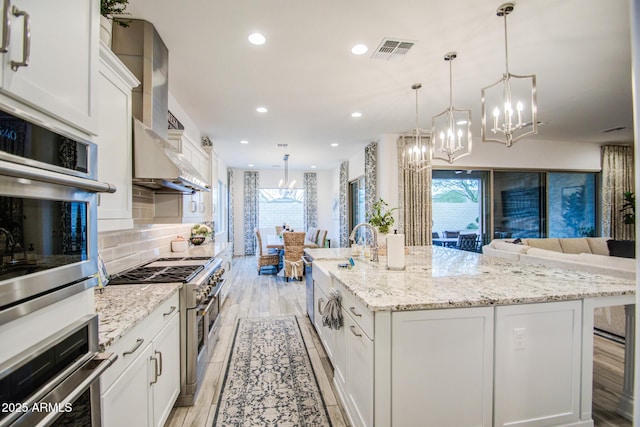 kitchen featuring visible vents, plenty of natural light, stainless steel appliances, and wall chimney range hood