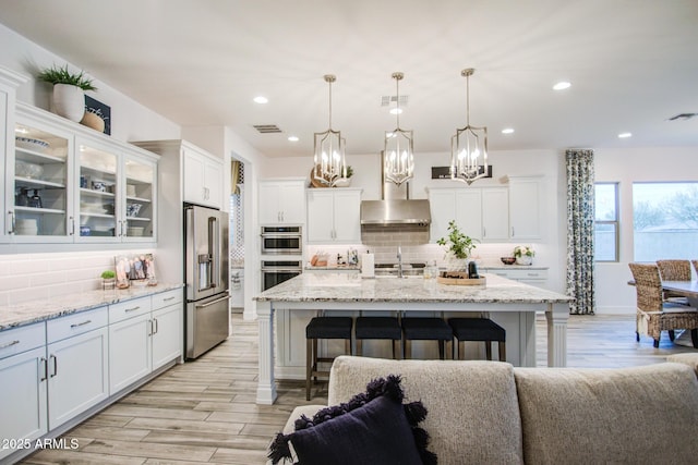 kitchen with visible vents, a breakfast bar, stainless steel appliances, under cabinet range hood, and white cabinetry