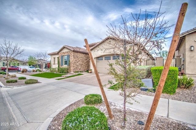 view of front of home featuring stucco siding, driveway, a tile roof, and a garage