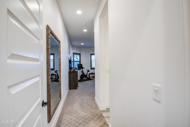 hallway featuring recessed lighting, baseboards, and light carpet