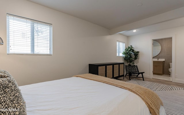 bedroom with hardwood / wood-style floors and ensuite bath