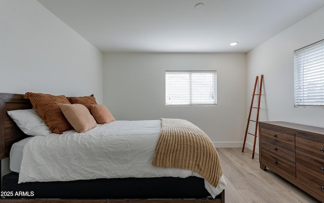 bedroom with multiple windows and light hardwood / wood-style flooring