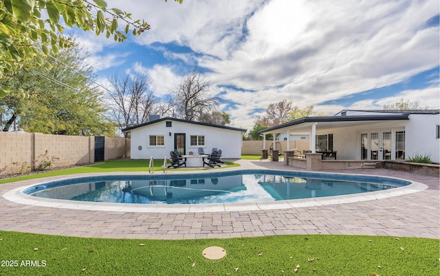 view of swimming pool featuring french doors, an outdoor structure, and a patio area