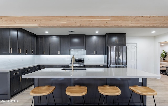 kitchen featuring sink, an island with sink, beamed ceiling, and appliances with stainless steel finishes