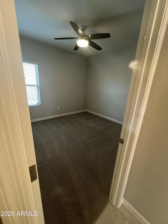 empty room with dark colored carpet and ceiling fan