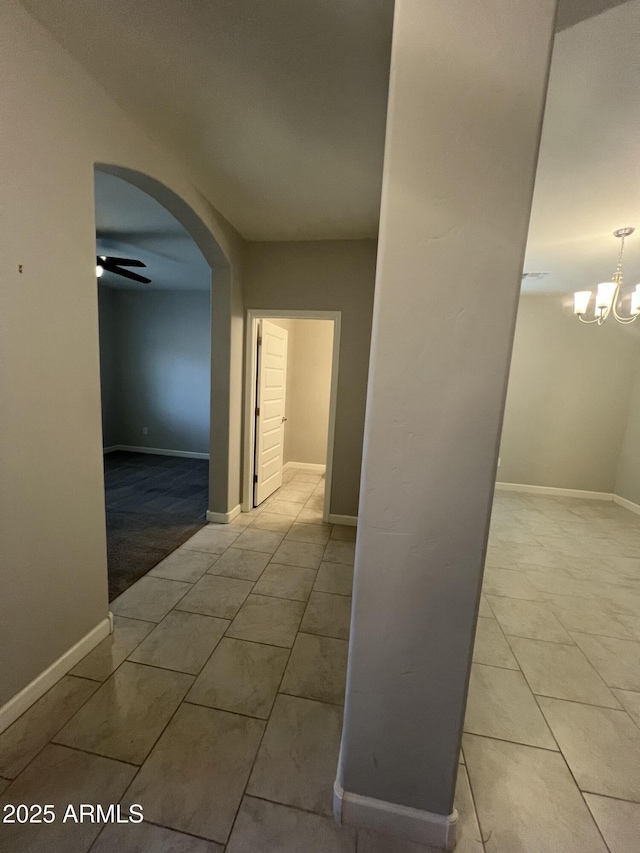 hallway with an inviting chandelier and light tile patterned floors