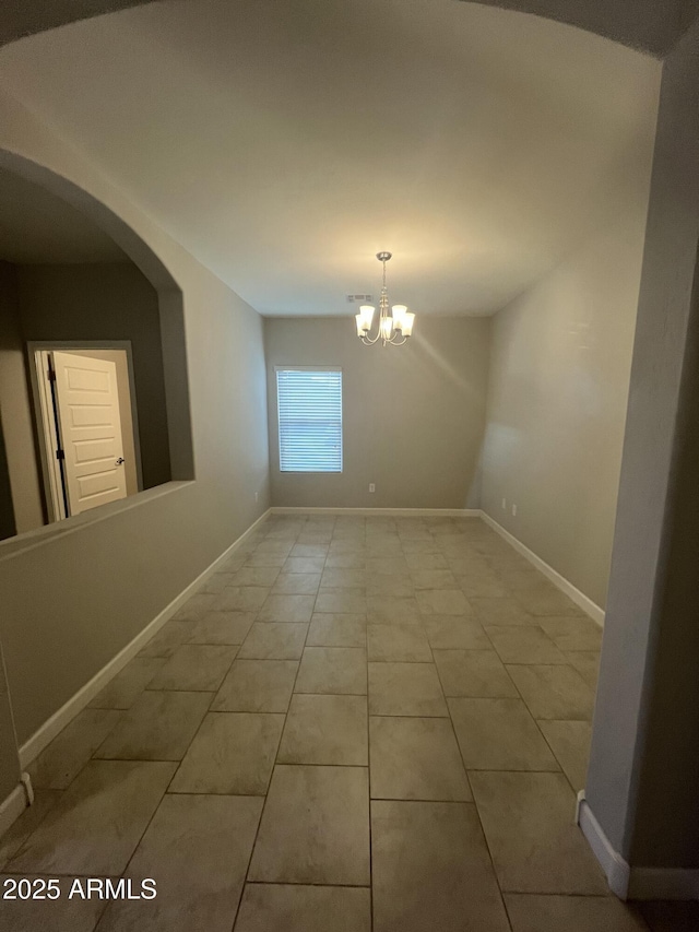 empty room with light tile patterned floors and an inviting chandelier