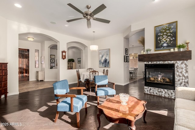 living room featuring a fireplace, dark wood-type flooring, and ceiling fan