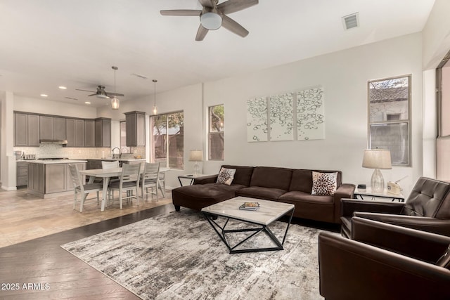 living room featuring ceiling fan, sink, and light wood-type flooring