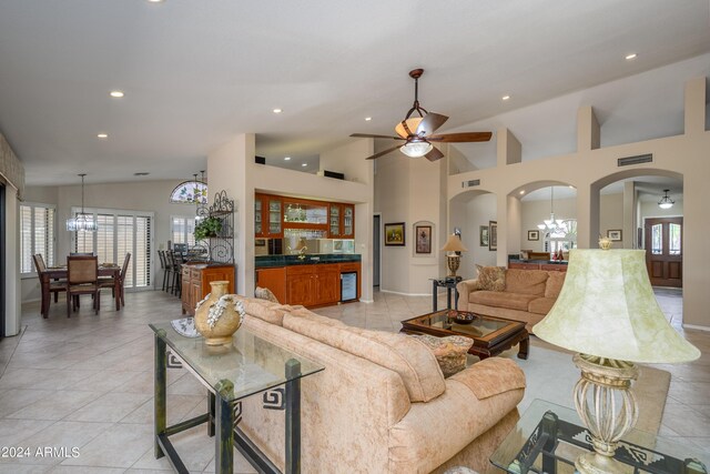 tiled living room featuring ceiling fan with notable chandelier, vaulted ceiling, and wine cooler