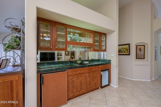 bar featuring light tile patterned floors, wine cooler, and sink